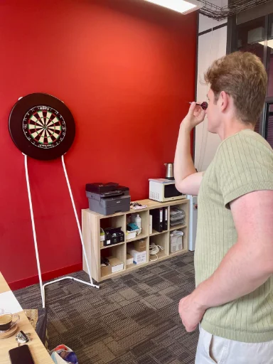 A PolicyMate team member playing darts while waiting for Claude
